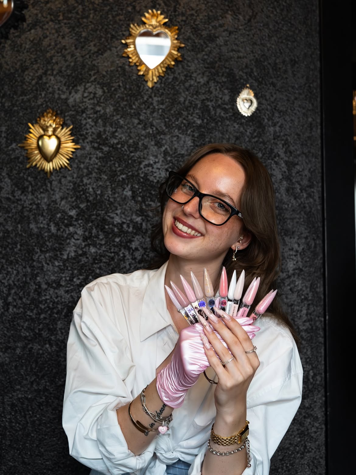 Axelle, souriante, un éventail d'échantillons de couleurs d'ongles à la main